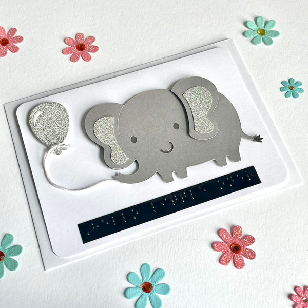 Elephant new baby card on a white back ground. The card is surrounded by pink and blue paper flowers.